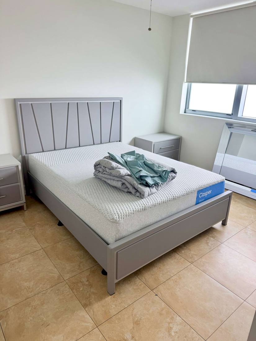 Gray bed frame, nightstands and mattress set up in a bedroom