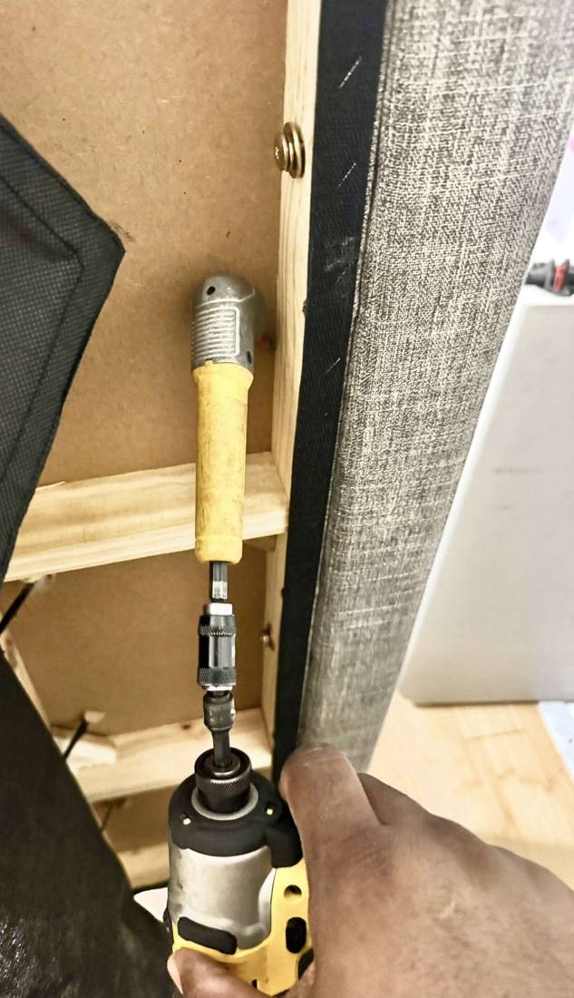 Close-up of a bed headboard being fastened with a power drill